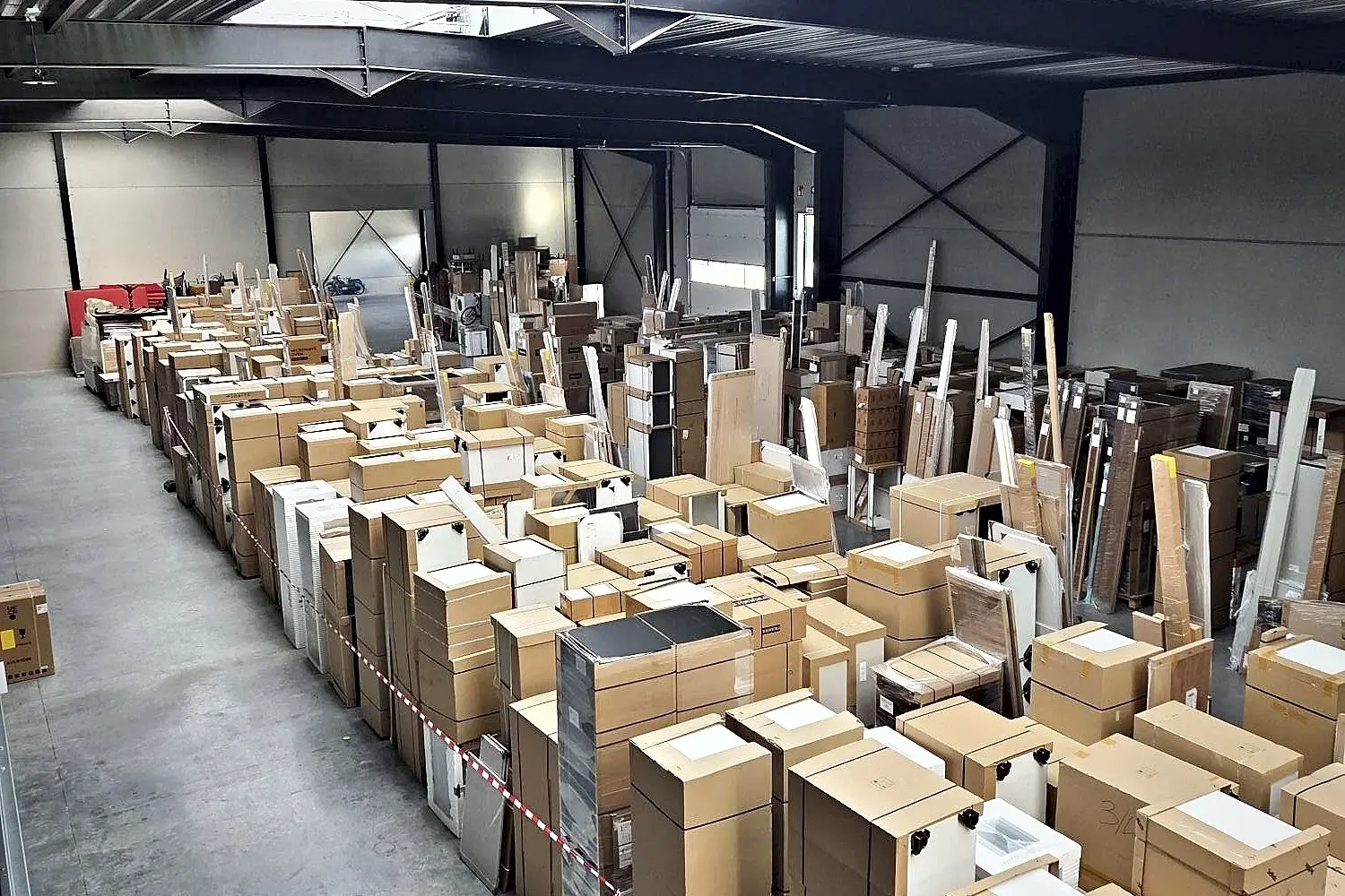 De opslaghal van De Vogelaere in Deinze, met ingepakte goederen netjes gestapeld op pallets